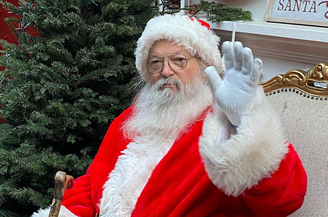 santa seated before a christmas tree