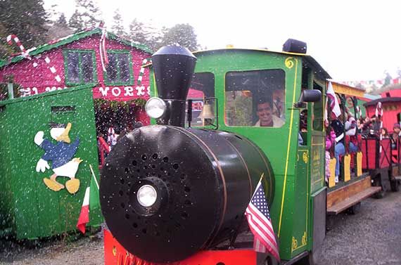 green train engine and cars in front of the elves workshop